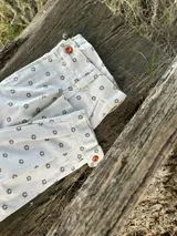 Bombacha de campo de lino color beige con estampado de pequeñas flores oscuras. Presenta pinzas frontales, cierre de botones en la cintura y pasacintos.