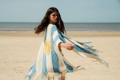 Ruana tejida en hilo de algodón con rayas horizontales anchas en color verde y blanco, con flecos en el borde inferior.