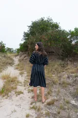 Vestido túnica midi de corte recto, color azul marino con rayas verticales blancas, mangas cortas abullonadas y lazo ajustable en la cintura.