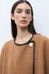 Capa color tostado con vivos en contraste de color negro, cierre frontal con un botón grande y un bolsillo lateral.