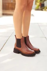 Botas Chelsea de cuero color marrón, con elástico lateral negro y suela track negra gruesa. Presentan un detalle texturado en el talón.