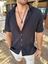 Camisa de manga corta con textura tipo waffle, color negro, con cuello clásico y cierre frontal de botones claros.