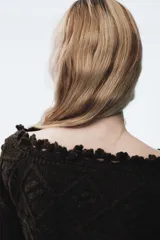 Jersey de punto color marrón oscuro con diseño de ochos y rombos, escote tipo barco con borde decorativo en ondas y manga larga.