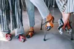 Zapatos tipo blucher de diseño artesanal, confeccionados en algodón con estampado floral multicolor sobre base negra. Presentan detalles en terciopelo color fresa, cierre con cordones rematados en borlas y suela de cuero.