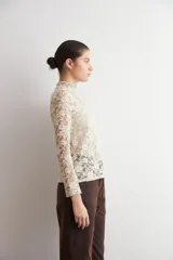 Media polera de encaje color beige con diseño floral, cuello alto y mangas largas.