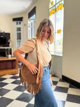 Cartera bandolera de cuero color camel con flecos largos en la parte inferior.