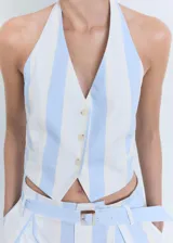 Top estilo chaleco con cuello halter, cierre frontal de tres botones y ajuste de hebilla en la espalda. Presenta un estampado de rayas verticales en tonos celeste y blanco, con dos bolsillos de ribete frontales y diseño entallado.