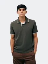 Remera polo blanca de manga corta, con cuello camisero y ribetes grises en cuello y puños. Cuenta con cierre frontal de botones y un pequeño logo bordado en el pecho.