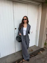 Conjunto de blazer y pantalón de lino gris con diseño de rayas diplomáticas. El blazer es de corte amplio con doble botonadura, y el pantalón es de corte recto y tiro alto.