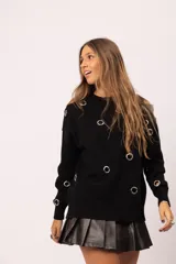 Buzo negro de cuello redondo con detalle de ojalillos metálicos plateados distribuidos en el frente y las mangas. Diseño de corte relajado con terminaciones acanaladas en cuello, puños y ruedo.