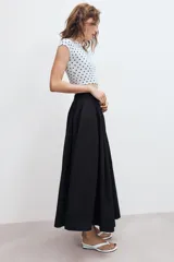 Falda midi de tiro alto en color verde militar, con diseño acampanado y cintura elástica. Presenta costuras verticales que definen su estructura y cierre lateral con cremallera oculta.