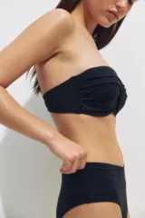 Top de bikini balconette negro con copas acolchadas, aros, varillas laterales y detalle girado en el centro. Incluye tirantes ajustables y extraíbles.