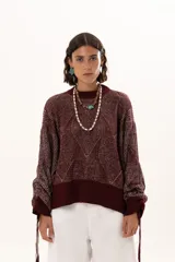 Buzo de punto color vino con diseño de trama geométrica, cuello redondo, mangas largas con puños ajustables mediante cordones y terminaciones acanaladas.