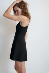 Vestido corto confeccionado en tejido elástico color negro, con escote redondo y tirantes finos.