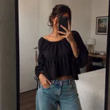 Blusa negra de manga larga abullonada con tiras ajustables en los puños, escote bote elastizado y diseño holgado con corte evase.