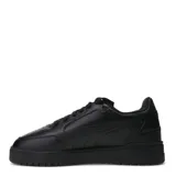 Championes urbanos Puma modelo Shuffle Downtown, de color negro con detalles en dorado. Presentan una capellada de cuero sintético con perforaciones en la puntera, cierre de cordones y suela de goma vulcanizada con tecnología SoftFoam+ para mayor amortiguación.