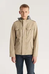 Campera color beige con capucha gris, cierre frontal con cremallera y botones a presión, cuatro bolsillos frontales con solapa y charreteras en los hombros.