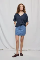 Falda de denim blanca de corte recto con bolsillos delanteros aplicados, costuras pespunteadas a contratono y cierre frontal con botón y cremallera.