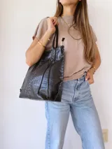 Bolso tote negro de cuero con textura tipo cocodrilo, doble asa larga y forro de tela.
