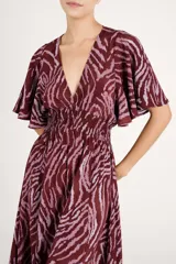 Vestido largo con estampado animal print abstracto en tonos bordó y rosado, escote en V pronunciado, mangas cortas amplias y cintura fruncida elastizada.