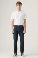 Pantalón de jean corte slim taper, de color azul oscuro con costuras en contraste. Presenta diseño de cinco bolsillos, cierre de botón y bragueta con cremallera.