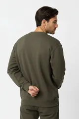 Buzo de cuello redondo color verde militar, de mangas largas con puños y dobladillo acanalados, y calce holgado.
