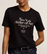 Remera slim de algodón negro, con cuello redondo, mangas cortas y estampa frontal "New York Atelier of Art" en color blanco.