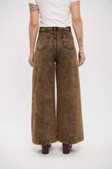 Pantalón de jean de corte wide leg con efecto de lavado ácido en tono marrón. Presenta tiro alto, cierre frontal con botón y bolsillos laterales.