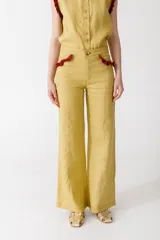 Pantalón de vestir mostaza, de corte palazzo, con bolsillos laterales y detalle de volados rojos en la cintura.