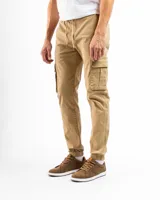 Pantalón cargo estilo jogger color verde oliva, confeccionado en algodón con spandex. Presenta cintura con elástico y pasadores para cinturón, cierre frontal y puños ajustados en los tobillos. Cuenta con múltiples bolsillos cargo laterales.