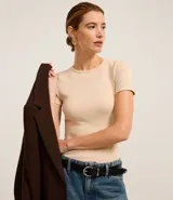 Blusa color beige de mangas cortas, confeccionada en tejido rib con textura acanalada y cuello redondo.