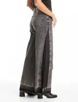 Jean de tiro alto y pierna ancha, con diseño de cinco bolsillos, cierre frontal con botón y detalle lateral en contraste de color negro. Presenta un acabado con ruedo deshilachado.