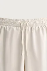Short de baño largo en color beige, confeccionado en tejido técnico con tacto aterciopelado. Cuenta con cintura elástica ajustable con cordón, bolsillos laterales y detalle de bolsillo trasero, además de forro interior.