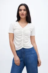 Remera color crudo con escote en V, cartera de botones y frunces.