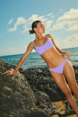 Bikini de dos piezas confeccionada en lycra texturada color lila. El corpiño es tipo top con breteles regulables y la bombacha es de corte vedetina con frente en V.