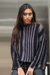 Sweater tejido de punto a rayas horizontales negras y plateadas, con cuello alto, mangas tres cuartos y calce oversize.