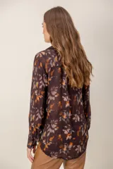 Camisa de manga larga con estampado de leopardo, cuello clásico y cierre frontal de botones. Presenta un corte holgado y puños abotonados.