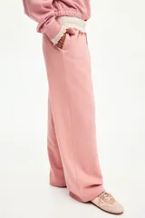 Jogging rosado de felpa con cintura elástica y cordón ajustable, de corte holgado y piernas amplias con bolsillos laterales.