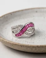 Anillo de plata 925 con diseño entrelazado decorado con rubíes baguette centrales y circonias cúbicas engastadas en pavé.