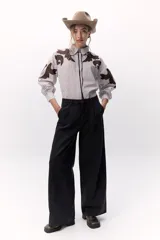 Camisa a rayas verticales blancas y marrones con bordados localizados y apliques metálicos. Tiene mangas abullonadas y cuello clásico con broche metálico.