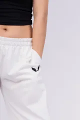 Pantalón deportivo blanco de corte recto con cintura elástica y logo bordado en negro.