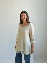 Sweater de punto color beige, de corte amplio y holgado, con escote redondo y mangas largas con presillas para arremangar.