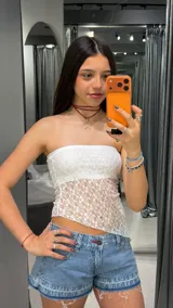 Top strapless blanco de encaje translúcido, con diseño asimétrico en el dobladillo inferior.