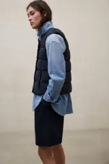 Chaleco acolchado blanco sin mangas, con diseño de franjas horizontales, cuello alto y cierre frontal con botones a presión. Modelo Olimpo de Ecoalf.