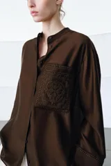 Camisa ZW Collection de color marrón oscuro, con cuello mao, manga larga con puños anchos y cierre frontal oculto por solapa. Cuenta con un bolsillo de parche en el pecho adornado con bordados a tono, los cuales también se repiten en los puños.
