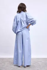 Pantalon de corte ancho y tiro alto, color azul marino, con bordados florales en color crema en la parte inferior de las piernas.