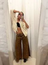 Pantalón de jean oxford marrón, de tiro medio-alto, con cortes verticales y costuras marcadas en las piernas, y diseño amplio y fluido.