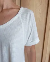 Remera blanca de algodón tramado, con escote en V y mangas cortas holgadas con dobladillo.