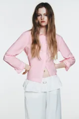 Pantalón blanco de nylon, tiro alto, con cintura elástica y detalle de sobrefalda o peplum superpuesto con hebilla metálica. Corte ancho y pierna recta.