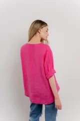 Blusa holgada de lino color verde brillante, con cuello mao abierto y manga corta enrollada. Presenta bordados estilo paisley en tono a tono y un botón de madera en el escote.